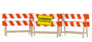 yellow black under construction sign on barrier