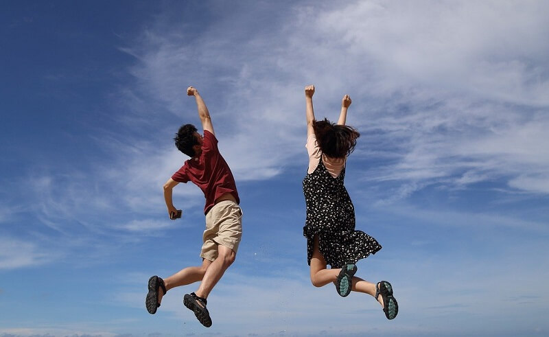 man and woman jumping high with sky background