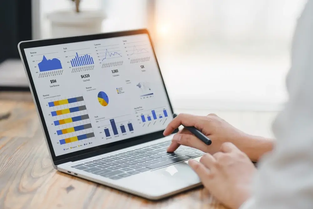 Professional in 5Tales analysing data graphs, charts on laptop